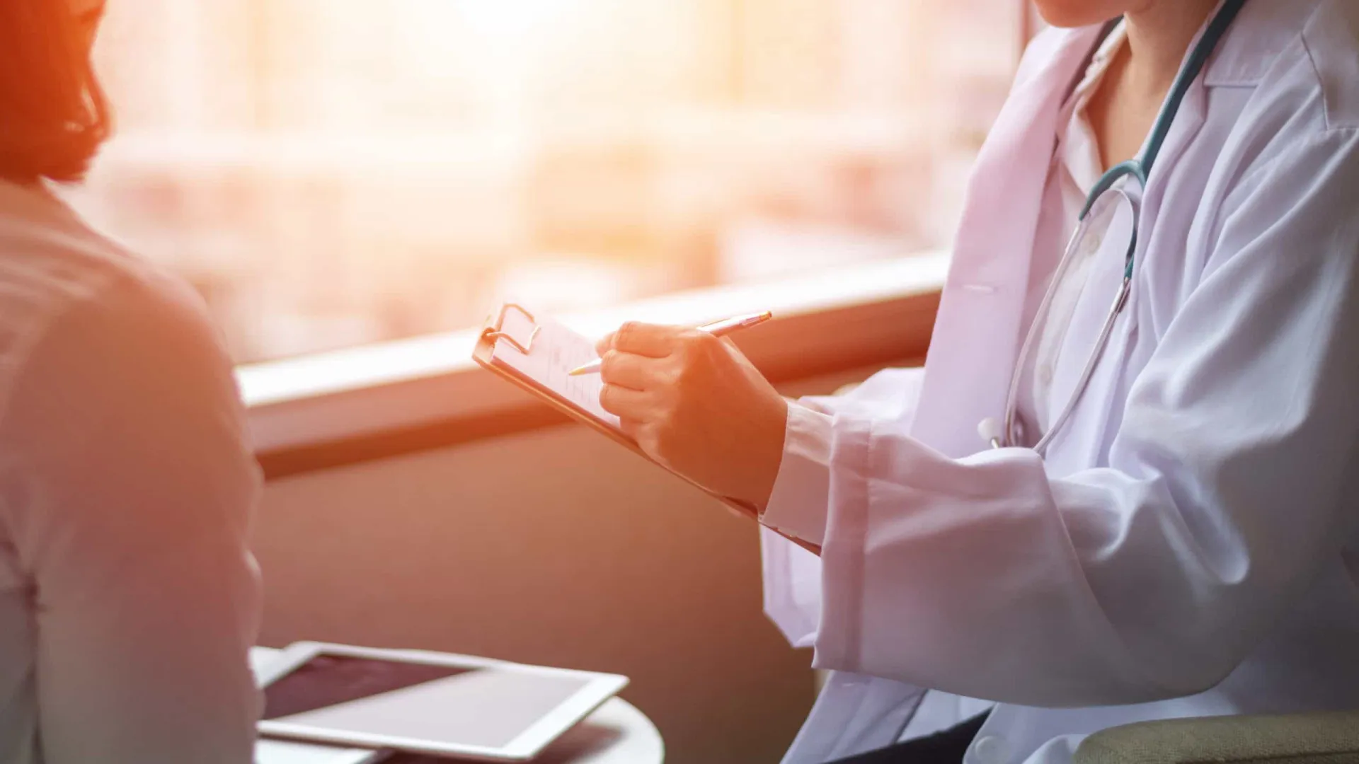 Paciente conversando com uma médica em um consultório, discutindo sobre seus sintomas.