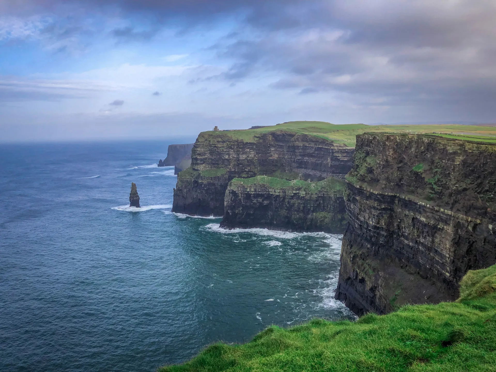 Penhascos dramáticos da costa da Irlanda, com o mar agitado batendo nas rochas.