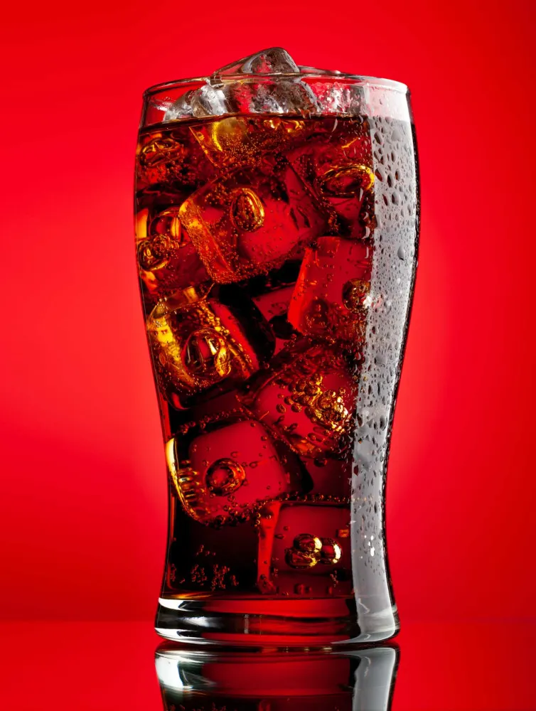 Copos cheios de refrigerantes de cola com gelo e gás borbulhando.