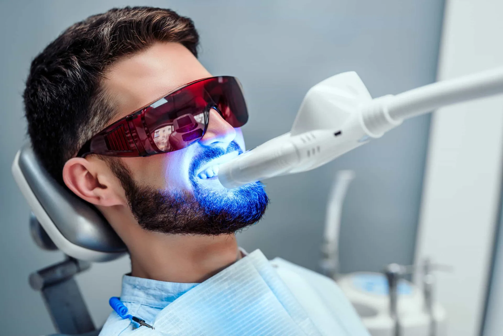 Um dentista aplicando um gel de clareamento nos dentes de um paciente em um consultório.