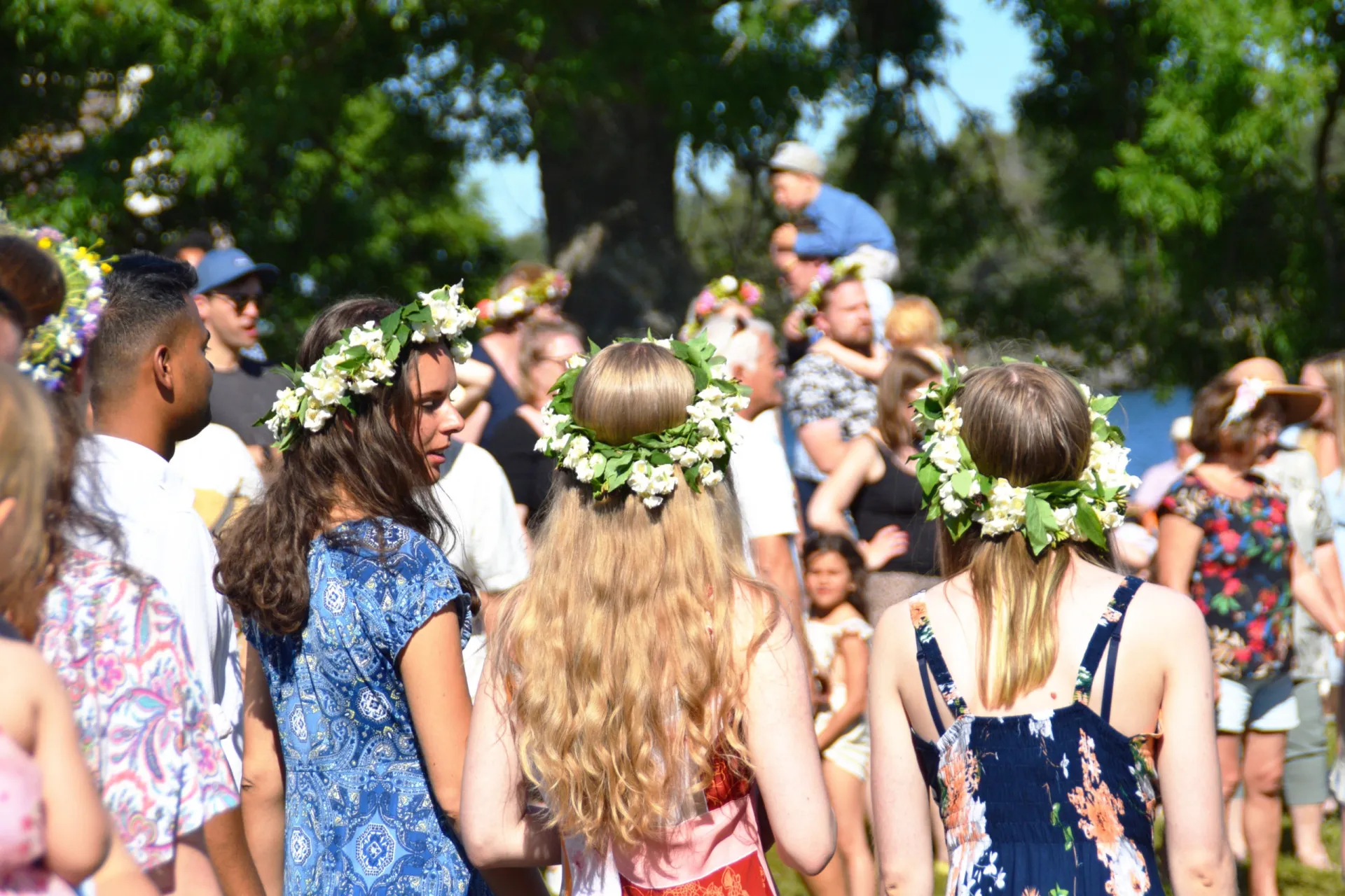 Pessoas celebrando o solstício de verão (Midsommar) na Suécia, dançando ao redor de um mastro decorado com flores.