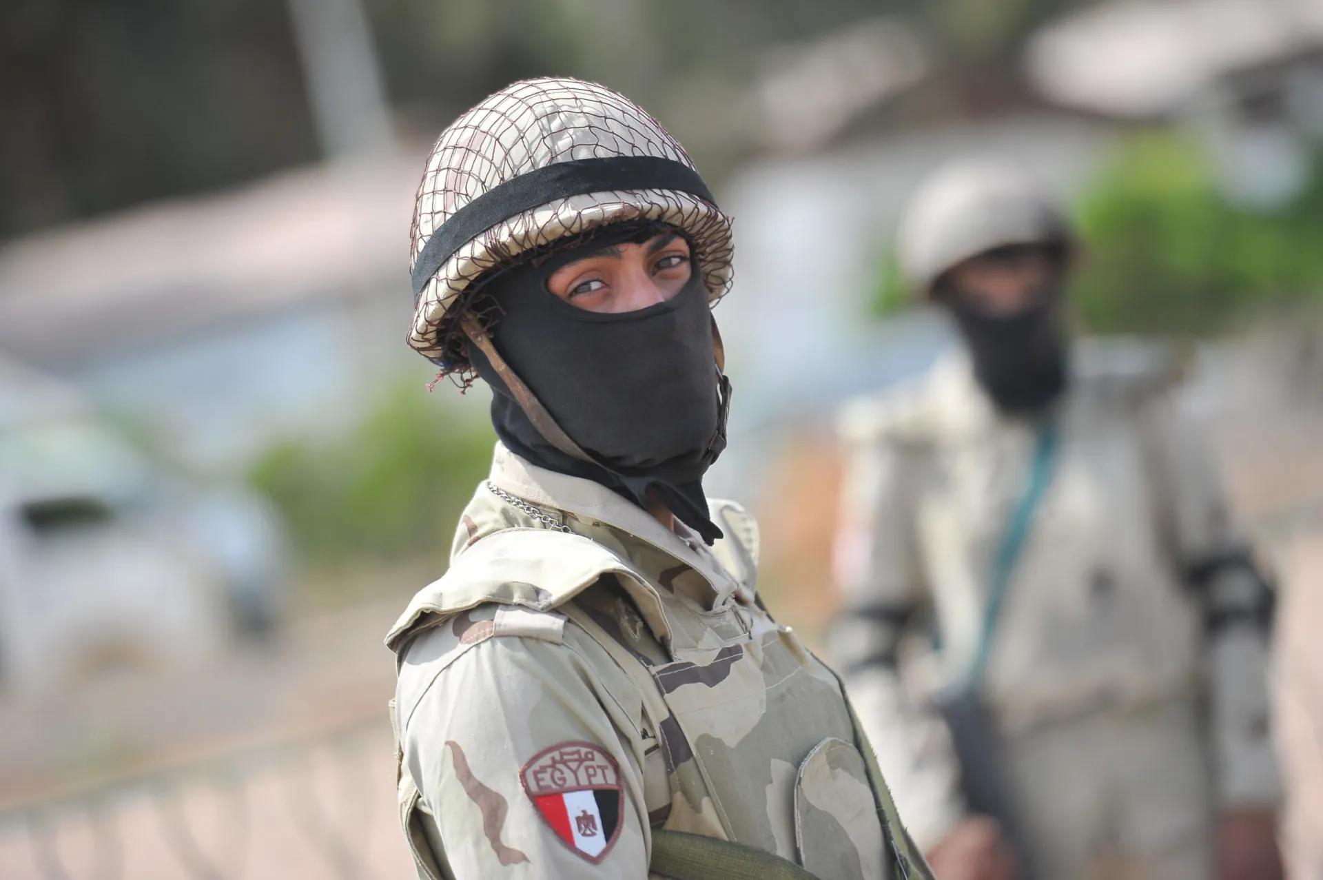 Homem egípcio mostrando seu certificado de conclusão do serviço militar.