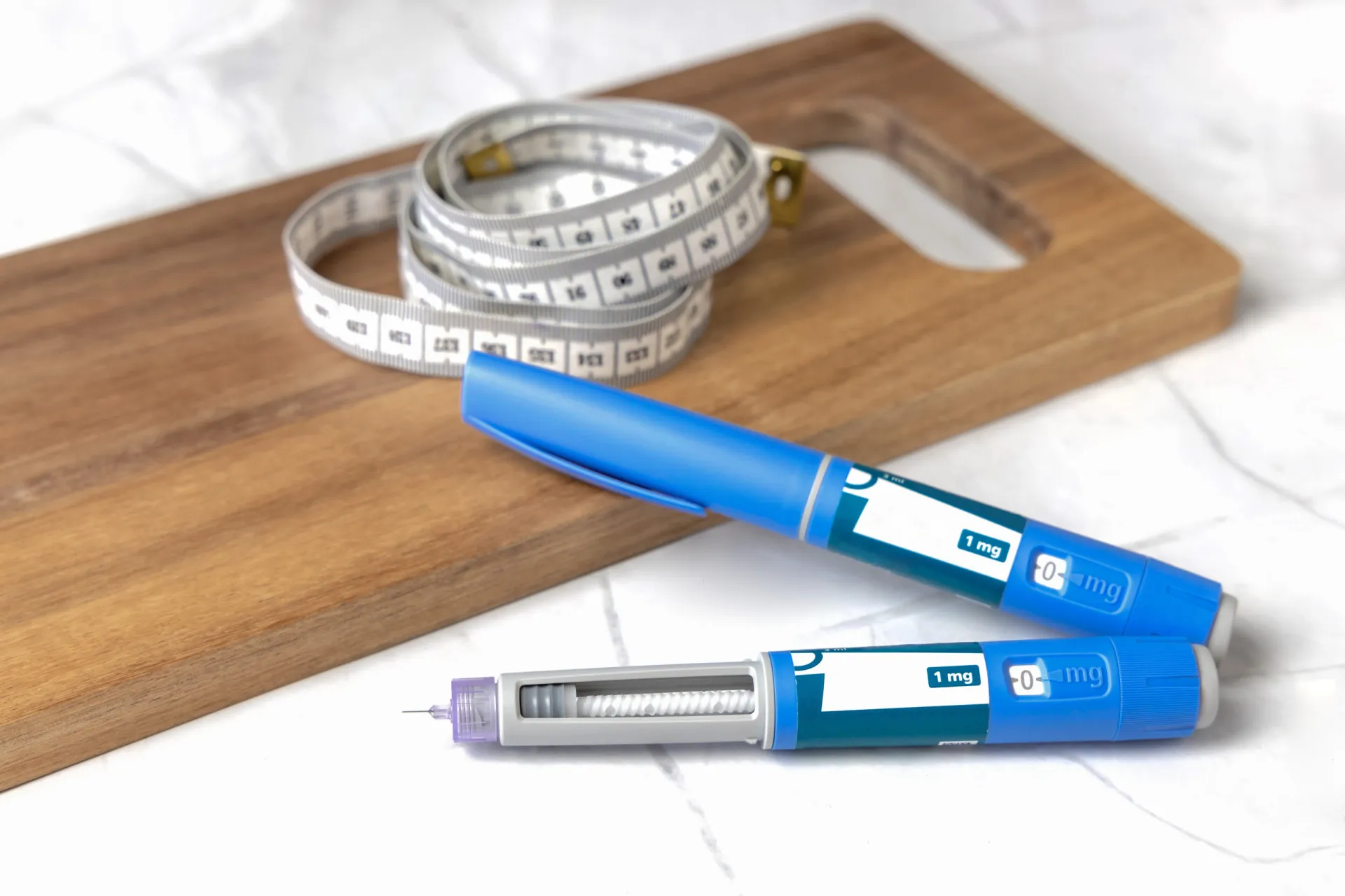 Caixa e caneta aplicadora de um medicamento GLP-1 como o Ozempic em uma mesa.
