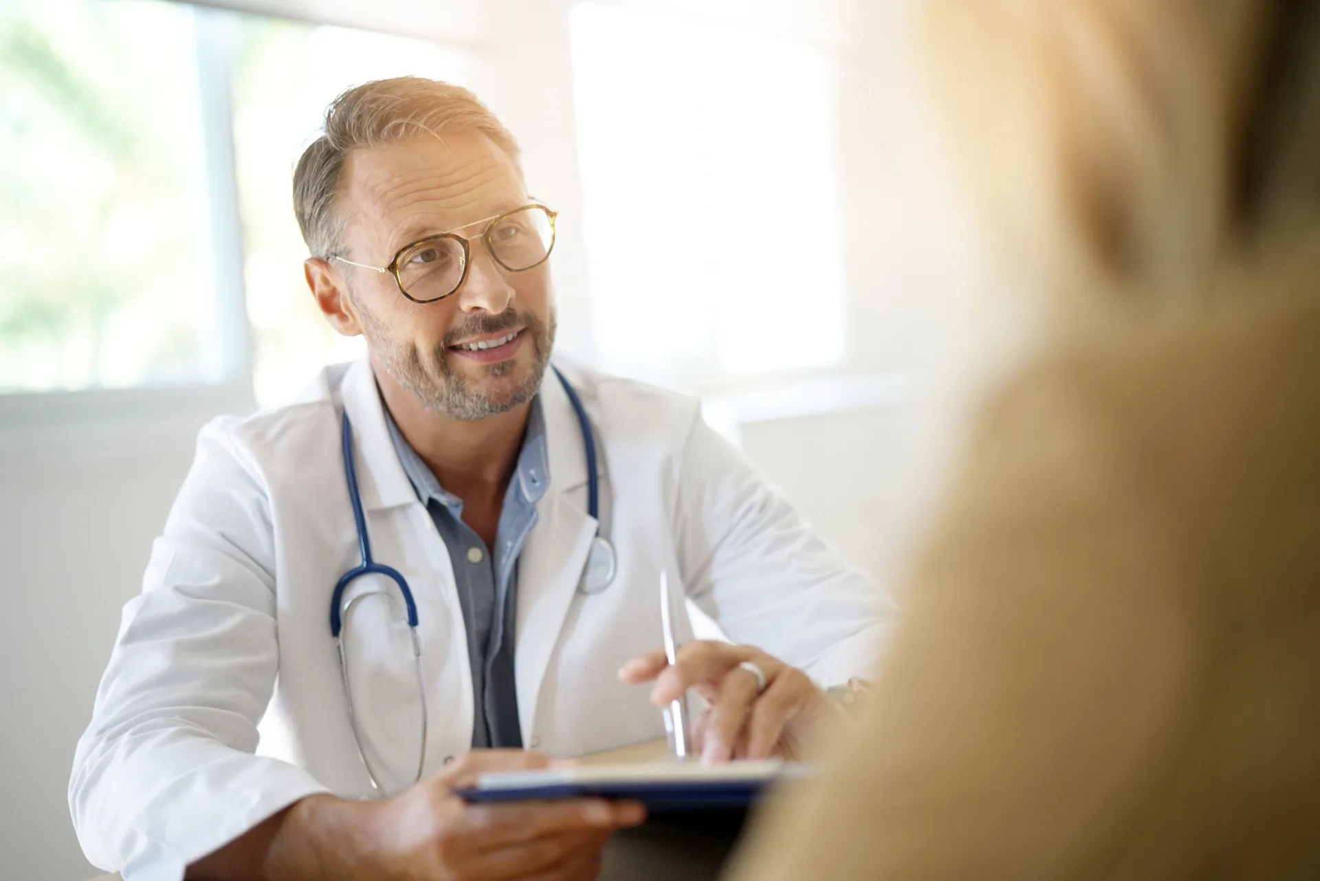 Paciente conversando com um médico em seu consultório sobre a decisão de parar a medicação.