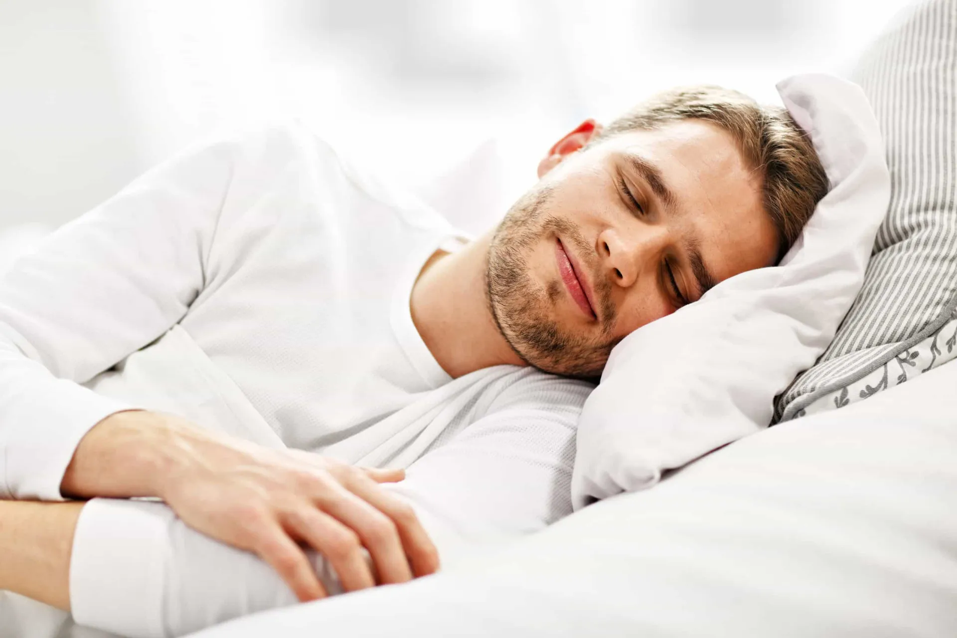 Pessoa deitada confortavelmente na própria cama, com uma expressão de alívio.