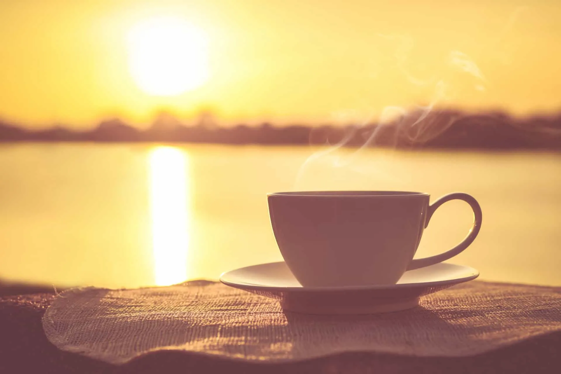 Fumaça saindo de uma xícara de café recém-passado em uma mesa de café da manhã.