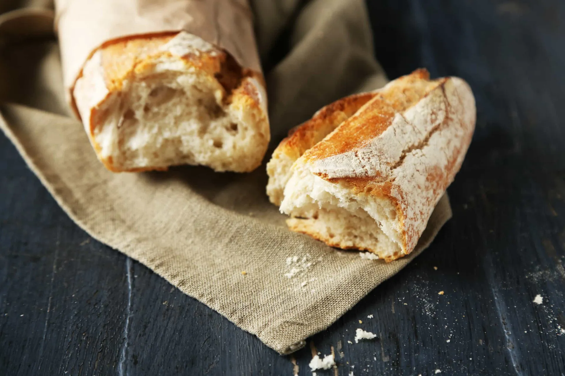 Mão quebrando a ponta crocante de uma baguete de pão fresco.