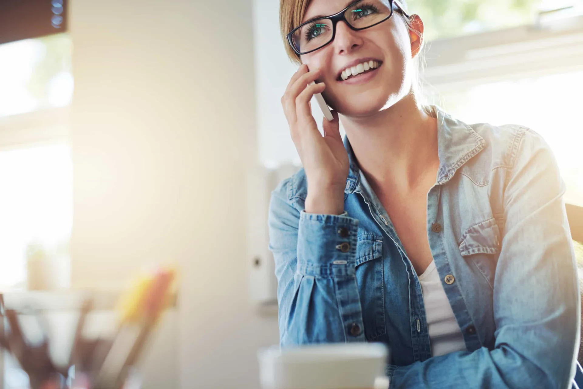 Atendente de call center sorrindo e falando com um cliente através de um headset.