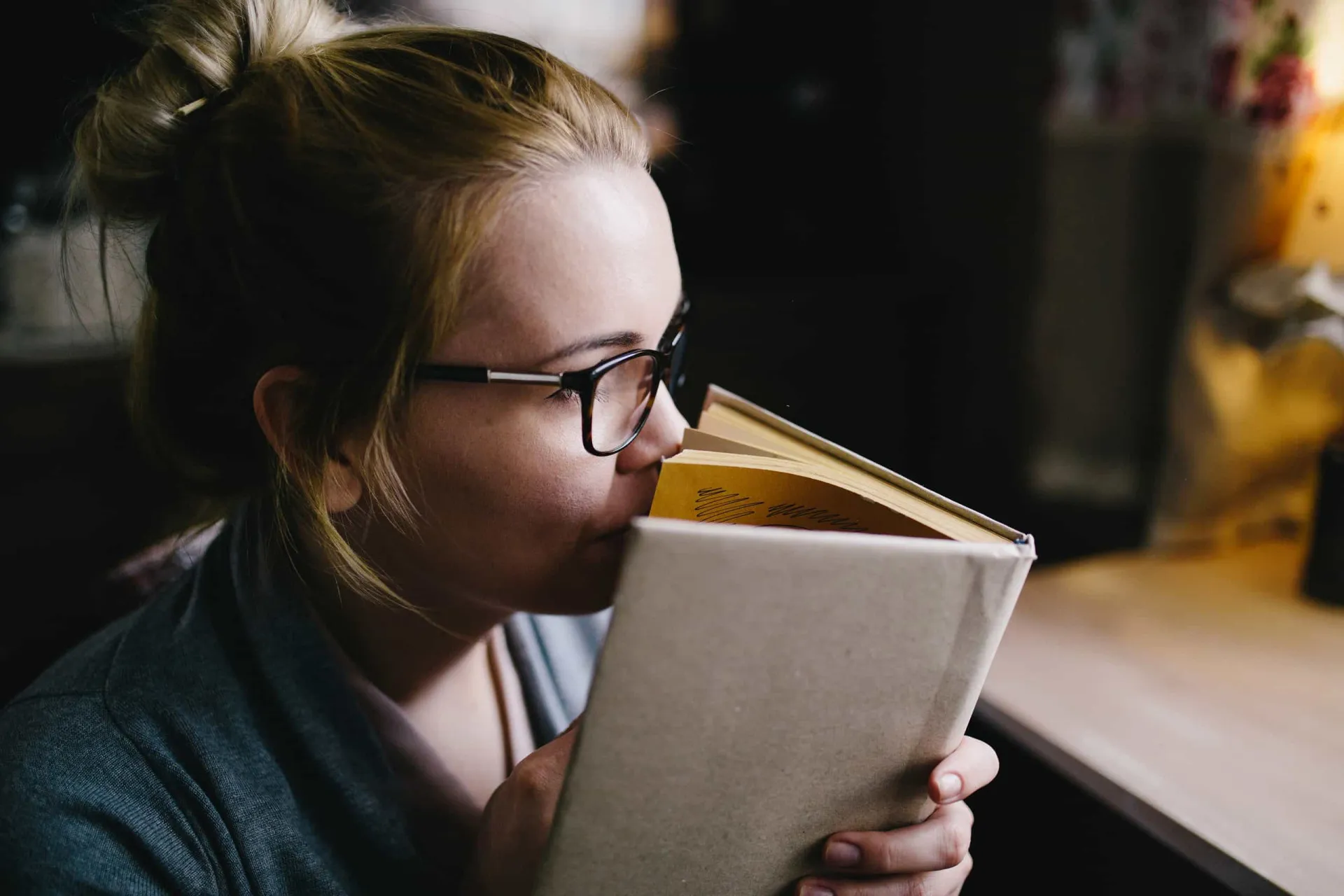 Pessoa segurando um livro novo aberto perto do rosto para sentir o cheiro das páginas.