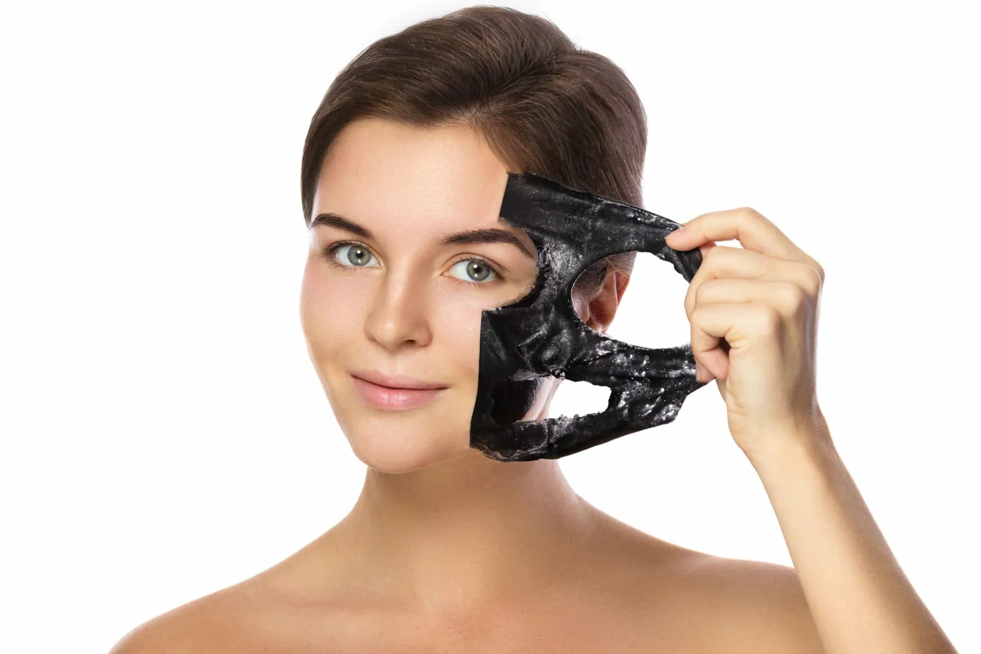 Mulher removendo uma máscara facial do tipo peel-off, revelando a pele por baixo.
