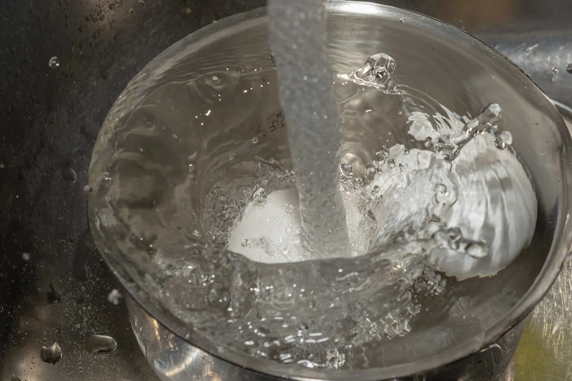 Vapor saindo de uma panela quente ao ser colocada debaixo de água fria na pia.