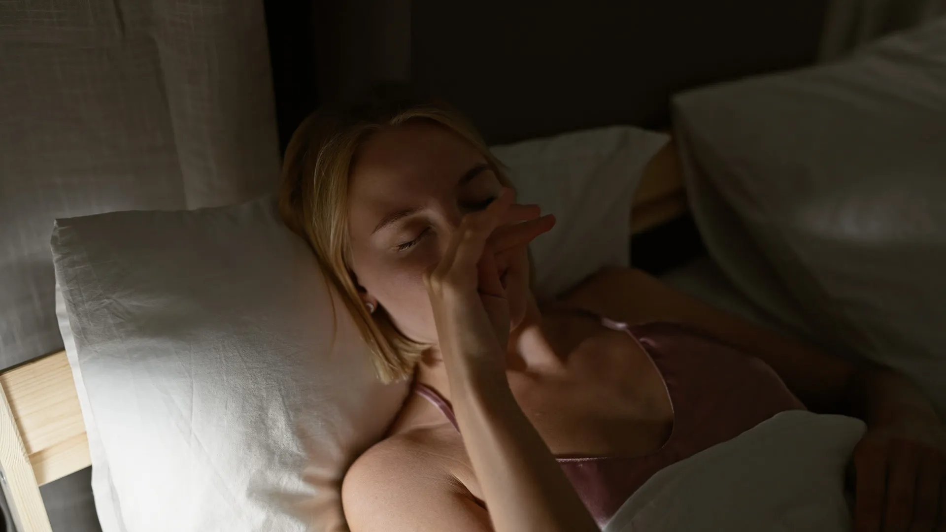 Pessoa ansiosa na cama, sentindo-se isolada no escuro.
