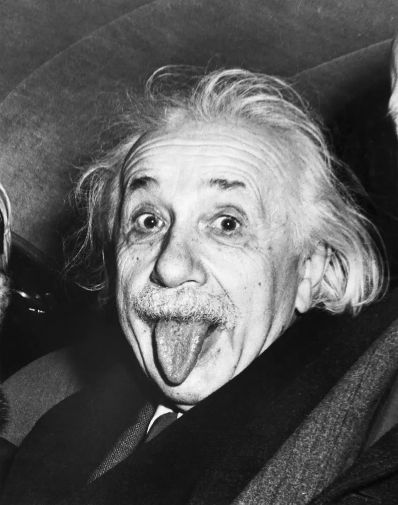 Albert Einstein no banco de trás de um carro, mostrando a língua para o fotógrafo.