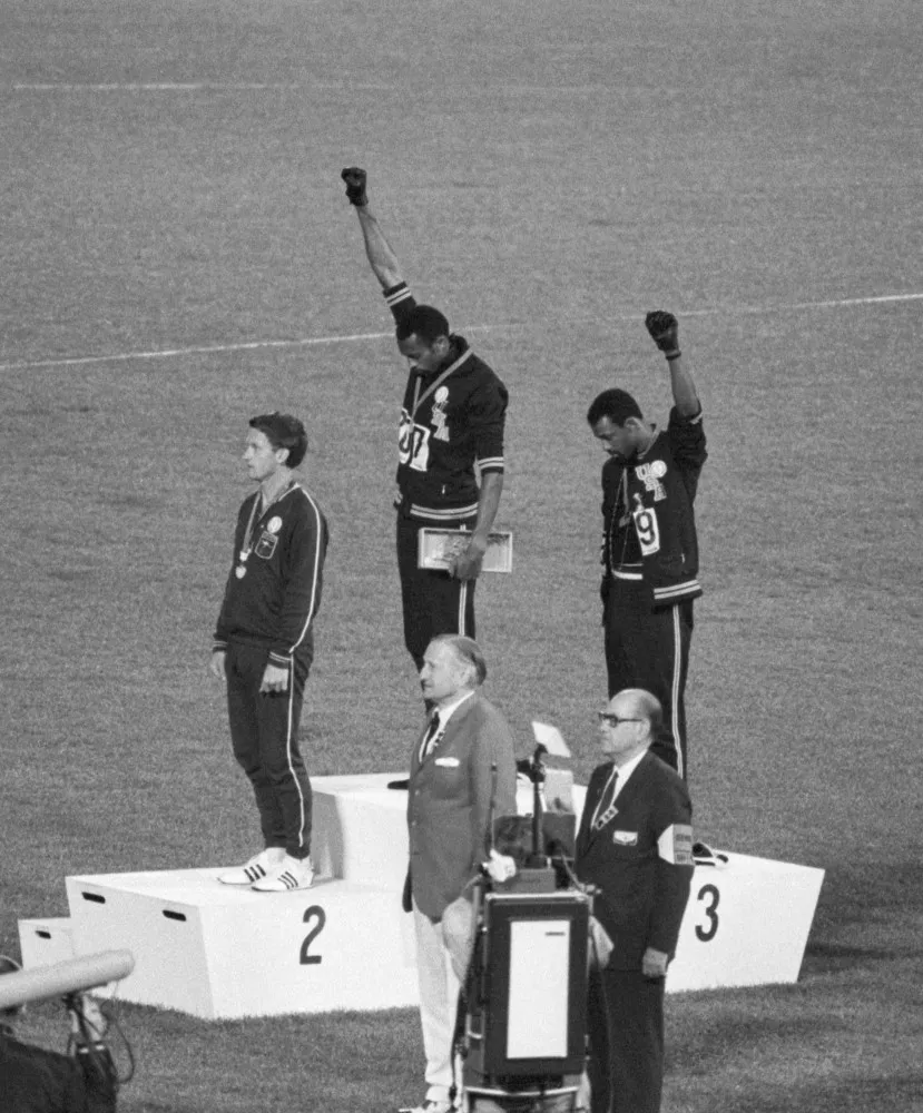Os atletas Tommie Smith e John Carlos no pódio olímpico com os punhos erguidos na saudação Black Power.