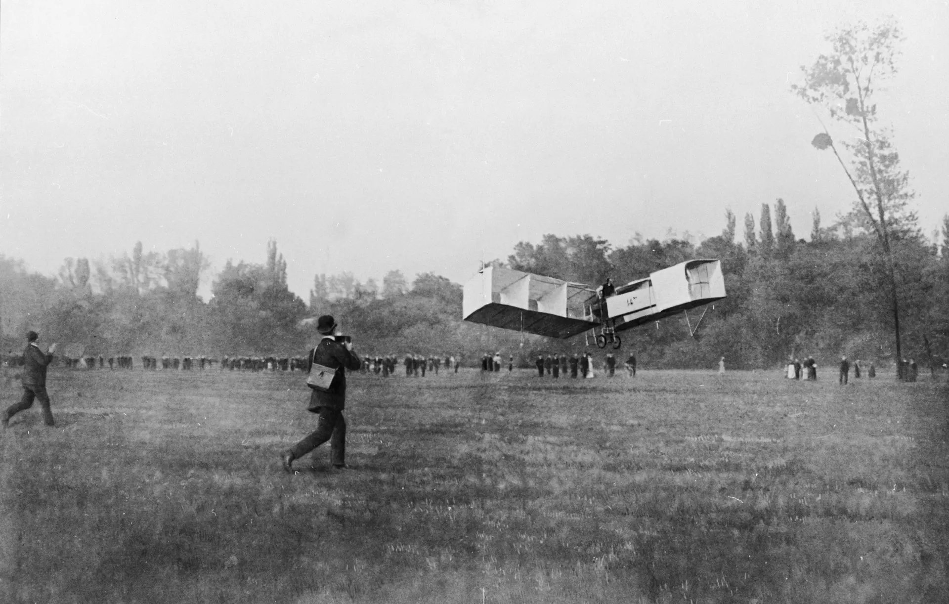 O avião 14-Bis, de Santos Dumont, em voo baixo sobre um campo em Paris, em 1906.