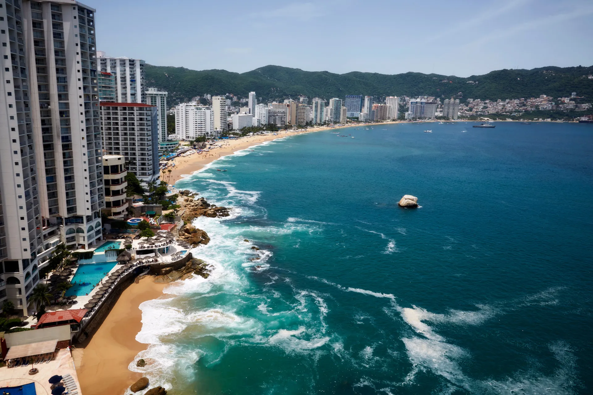 Vista da baía de Acapulco com hotéis e barcos.