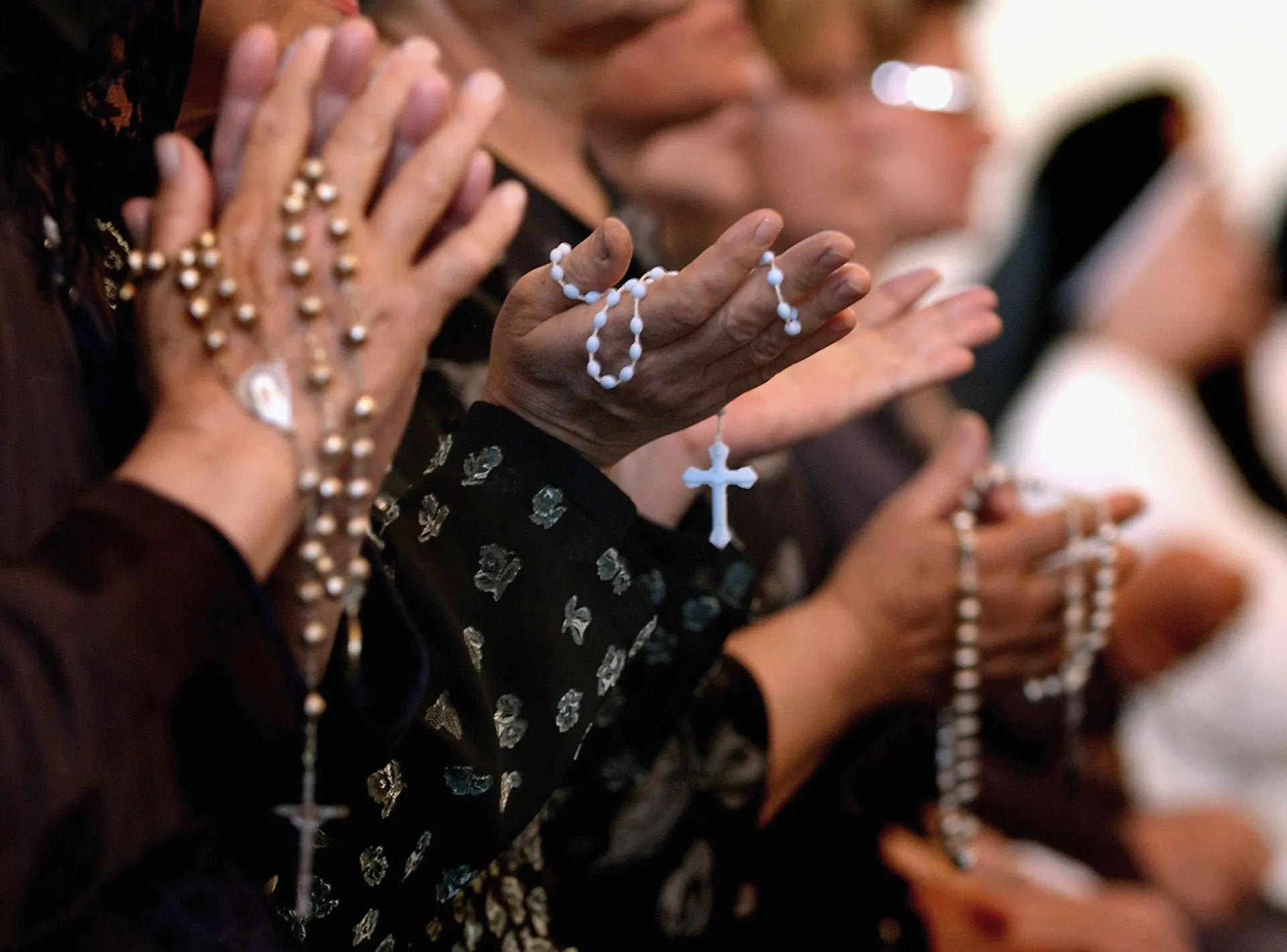 Mãos segurando um rosário, um objeto de devoção popular no catolicismo.