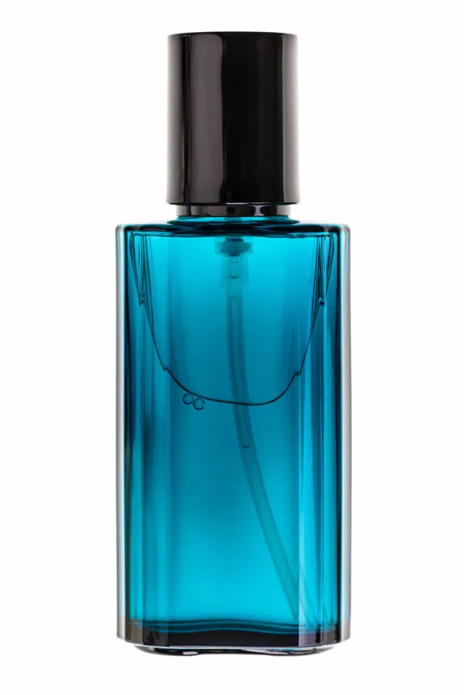 Frasco de perfume azul claro em uma praia, com o oceano ao fundo.
