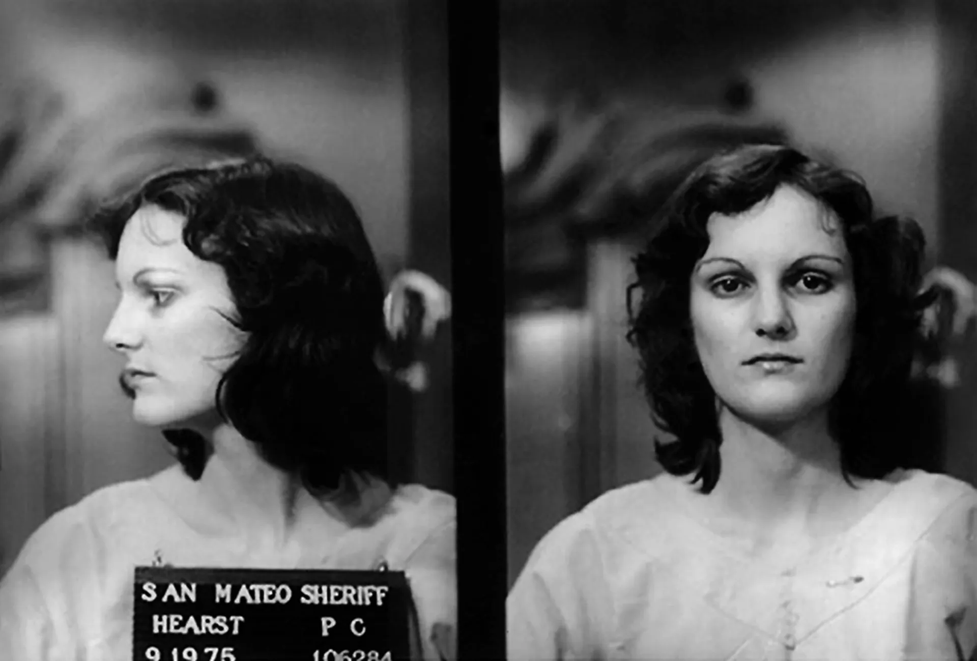 Patty Hearst sendo escoltada por agentes do FBI após sua captura, com uma expressão impassível.