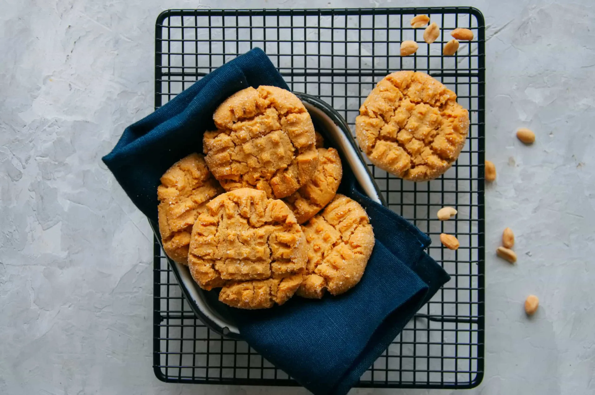Uma fornada de biscoitos de manteiga de amendoim dourados com a marca clássica de um garfo na superfície.