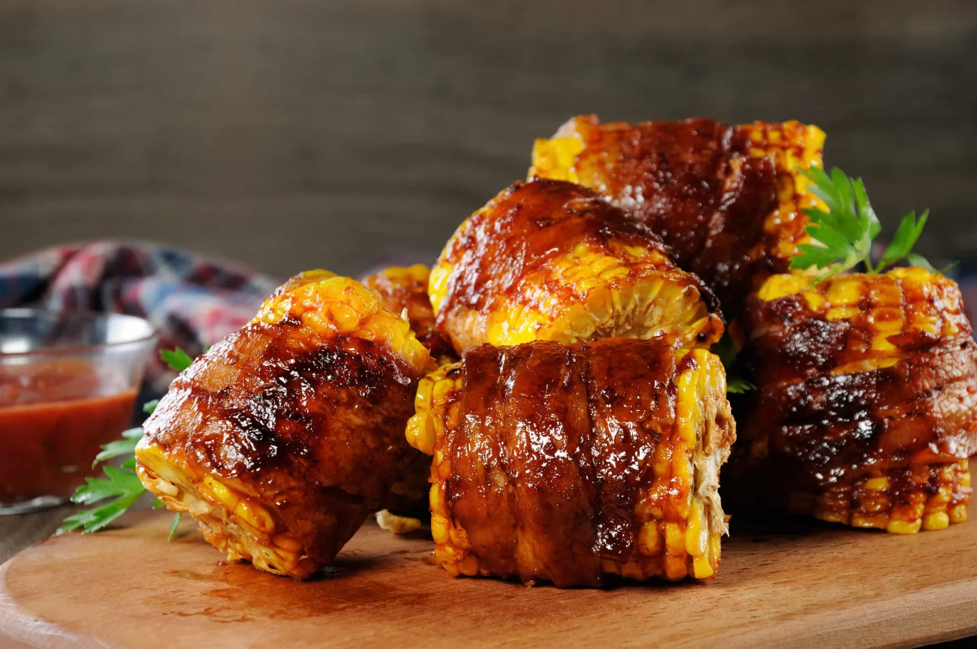 Espigas de milho envoltas em fatias de bacon crocante, grelhadas na churrasqueira.