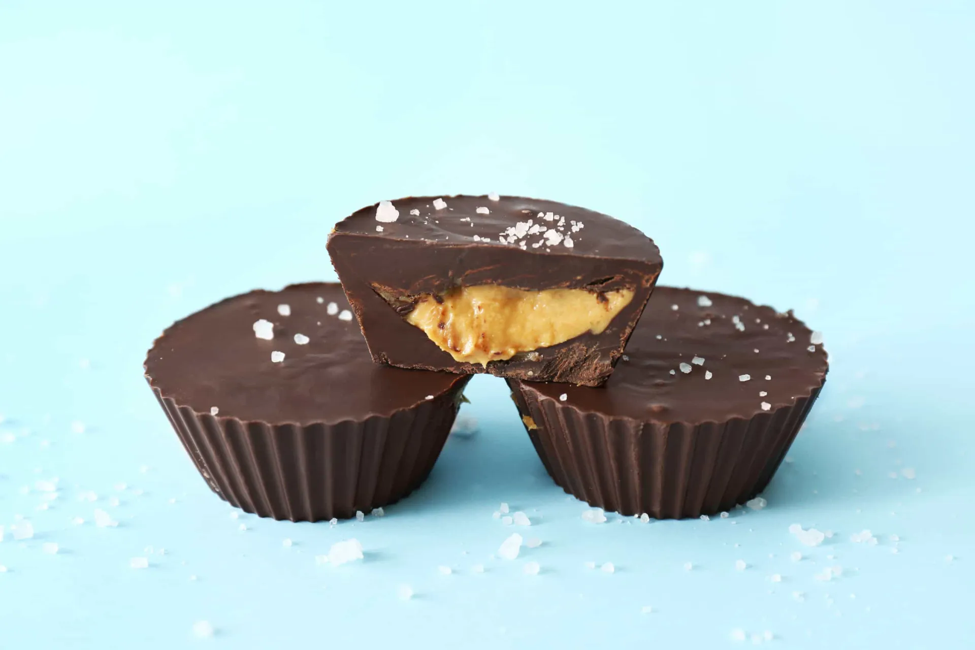 Mini tortinhas de chocolate com recheio cremoso de manteiga de amendoim, em forminhas de papel.