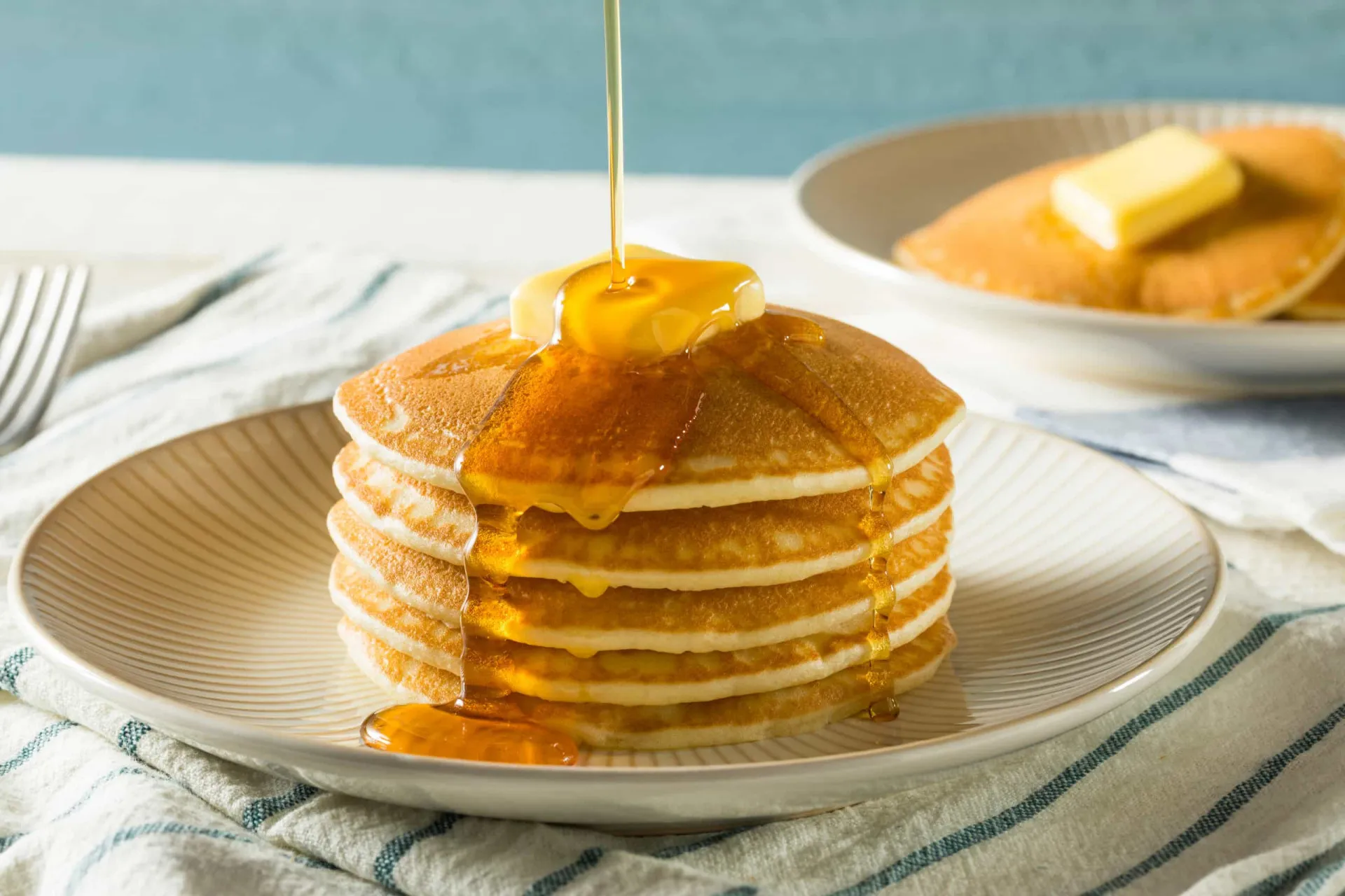 Pilha de panquecas pequenas e fofas feitas com banana, servidas com xarope.