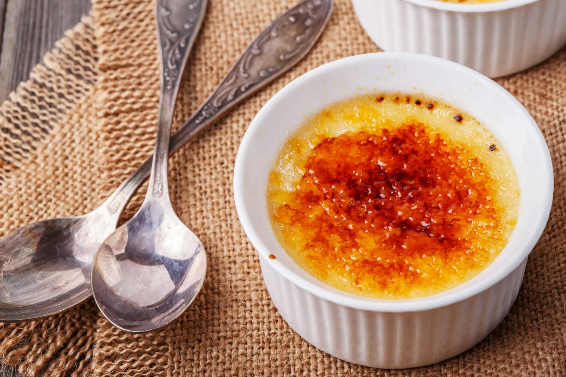 Close-up de um crème brûlée cremoso com a casquinha de açúcar perfeitamente caramelizada.