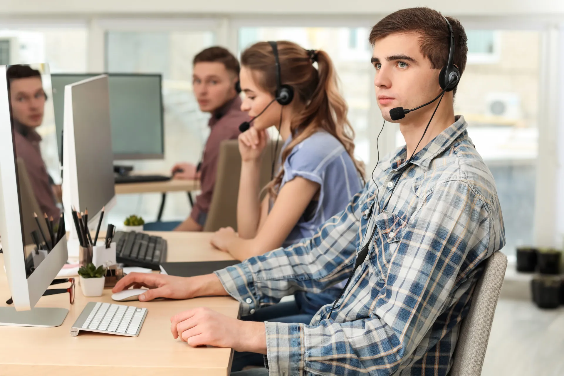 Uma operadora de telemarketing com fone de ouvido, parecendo cansada em um call center.
