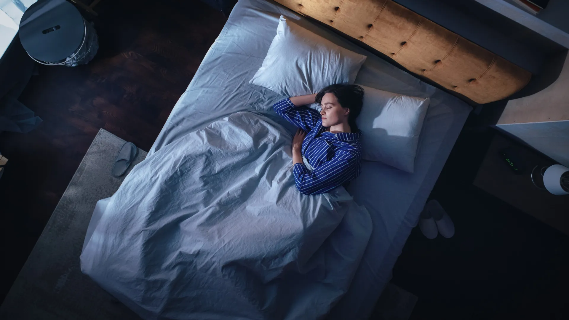 Mulher dormindo tranquilamente em uma cama confortável com iluminação suave.