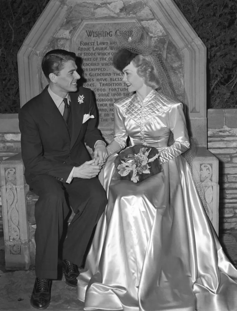 Ronald Reagan e a atriz Jane Wyman sentados em uma cadeira de desejos no dia do casamento em 1940.