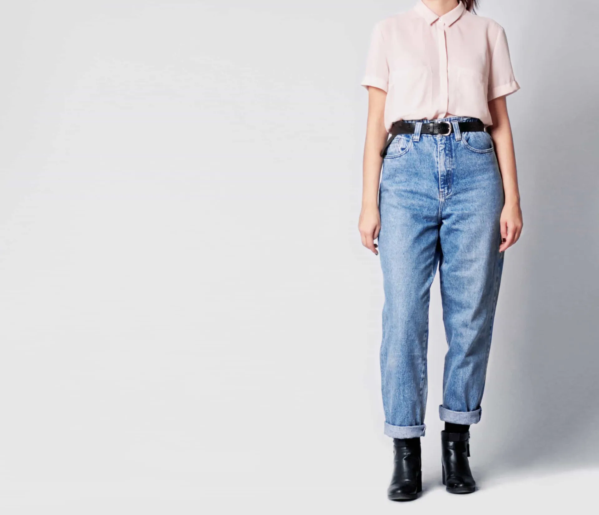 Mulher usando um modelo antigo de mom jeans, de cintura alta e corte reto que não valoriza a silhueta.