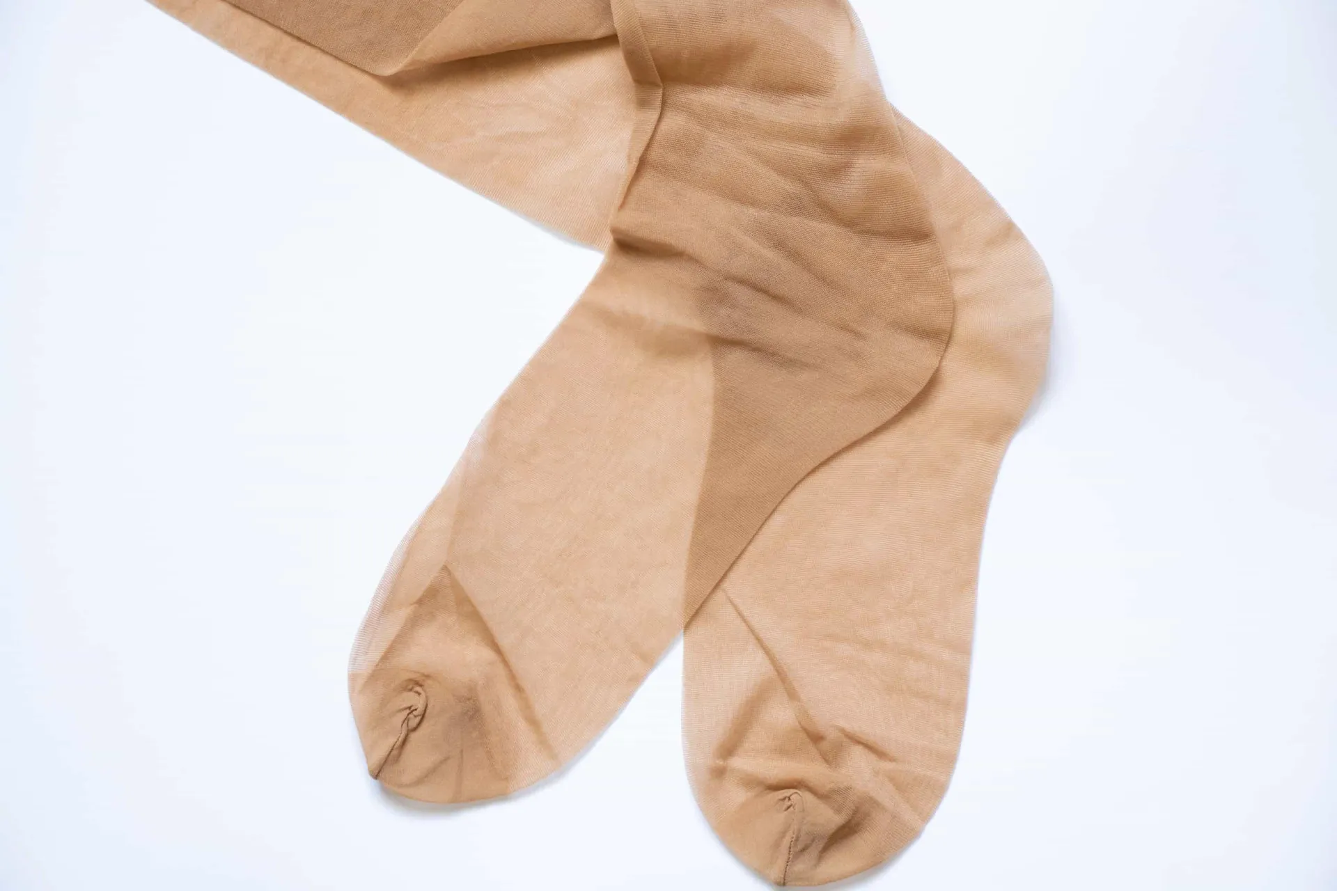 Pernas de uma mulher usando uma meia-calça cor da pele com brilho excessivo, um estilo datado.