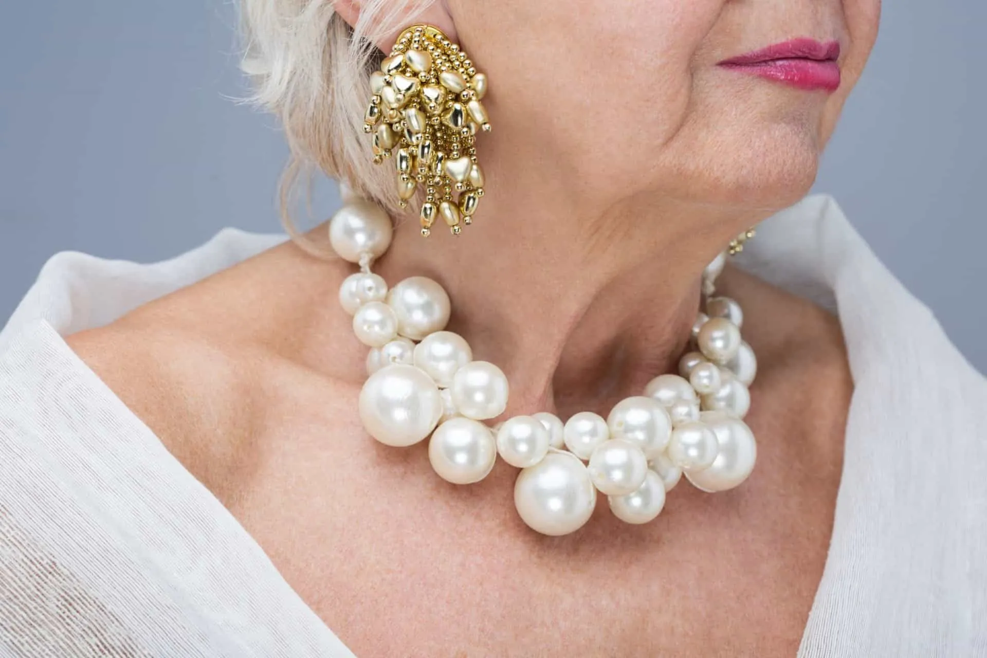 Mãos e pulsos de uma mulher cobertos por anéis e pulseiras barulhentas e exageradas.