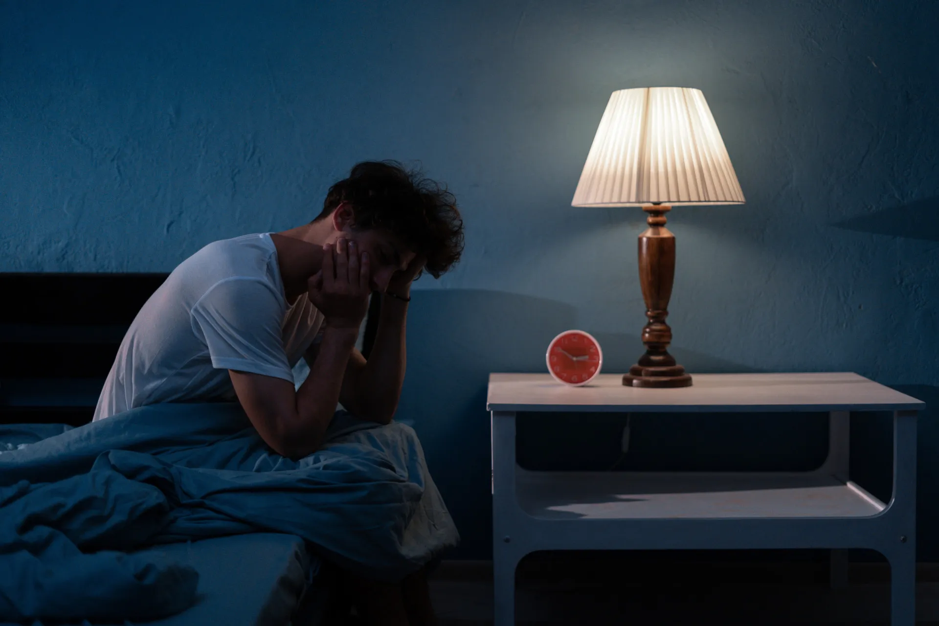 Uma pessoa deitada na cama, com insônia e dificuldades para dormir.