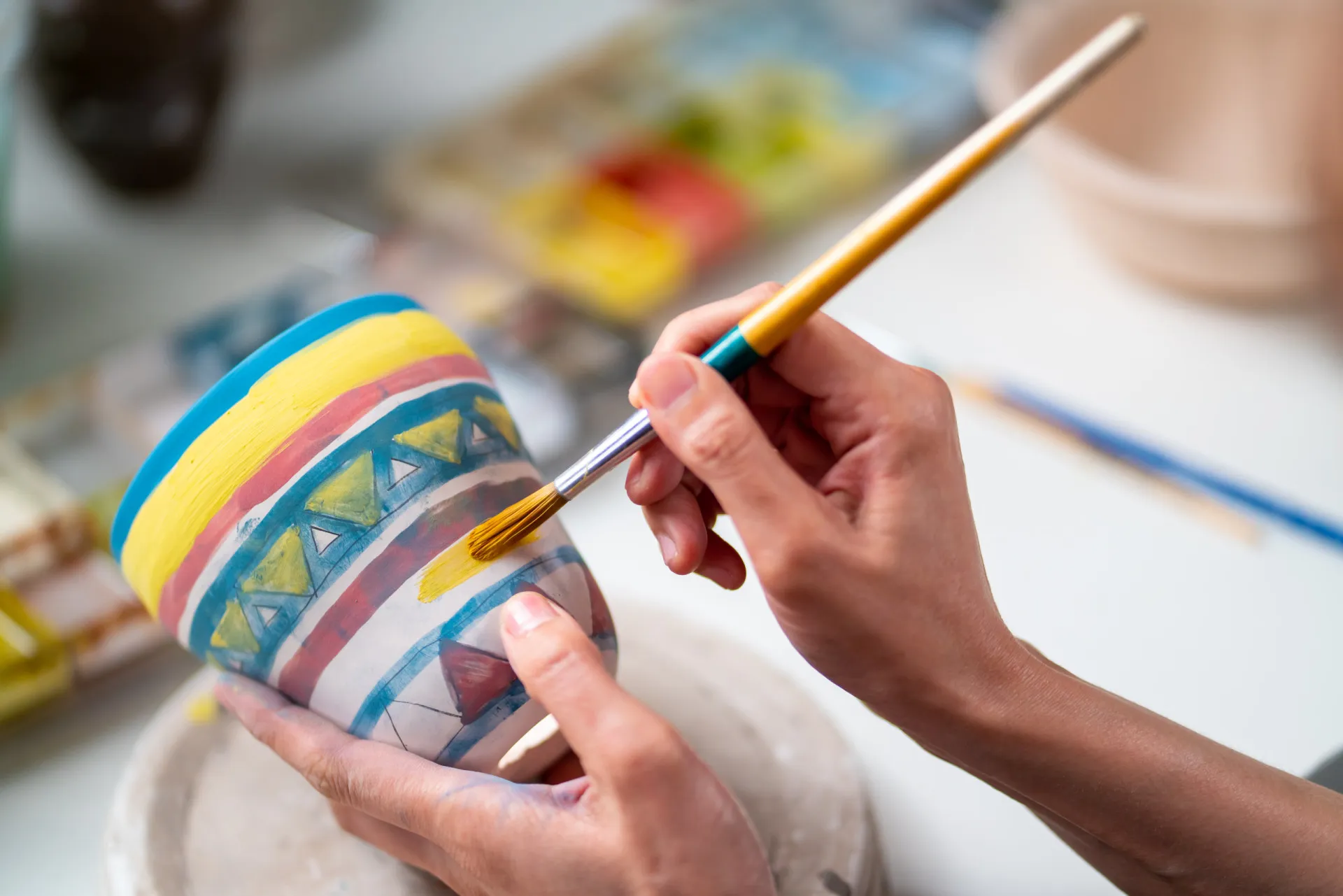 Uma pessoa olhando com apatia para um pincel e tintas, sem vontade de pintar.