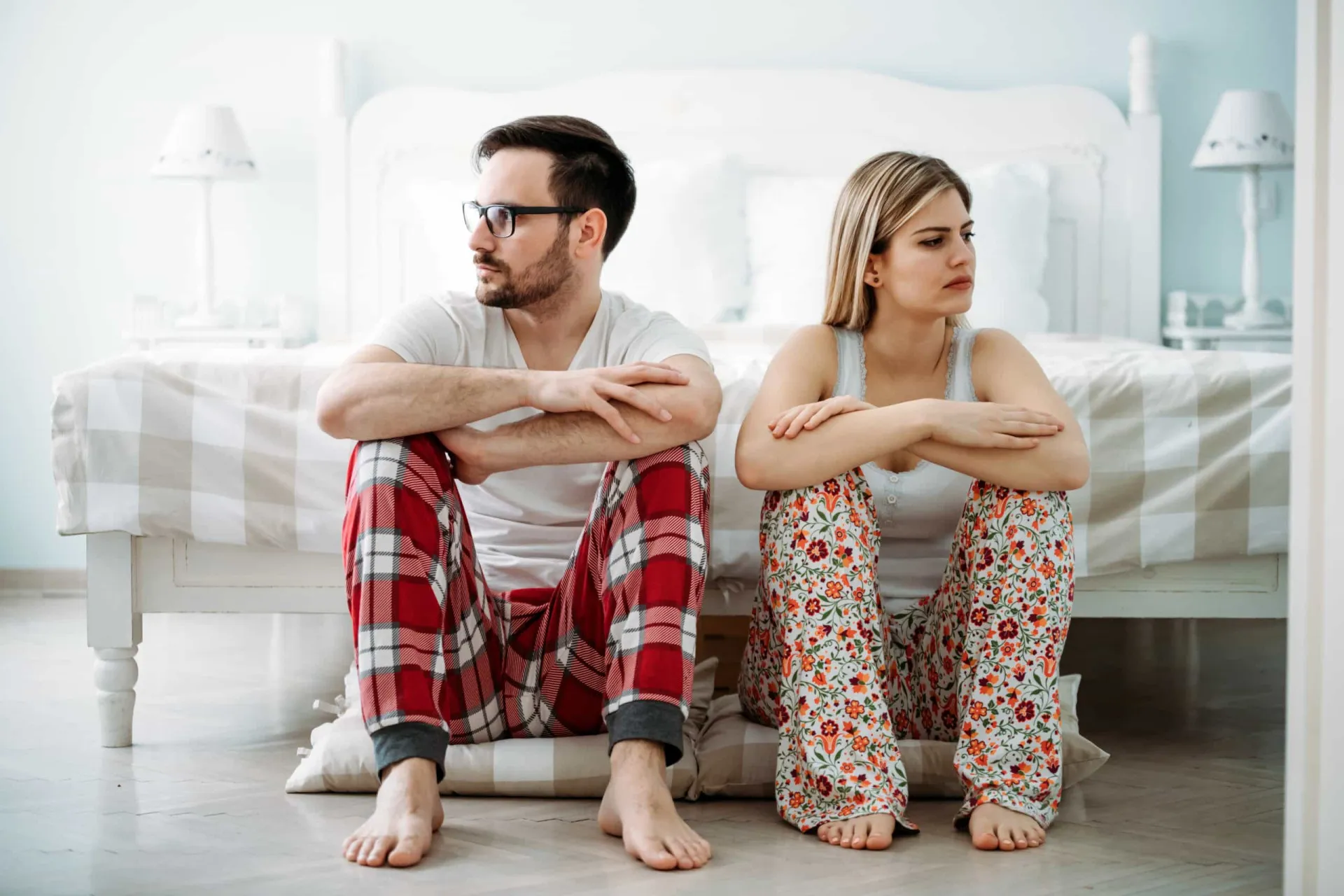 Um casal de costas um para o outro na cama, indicando falta de intimidade.