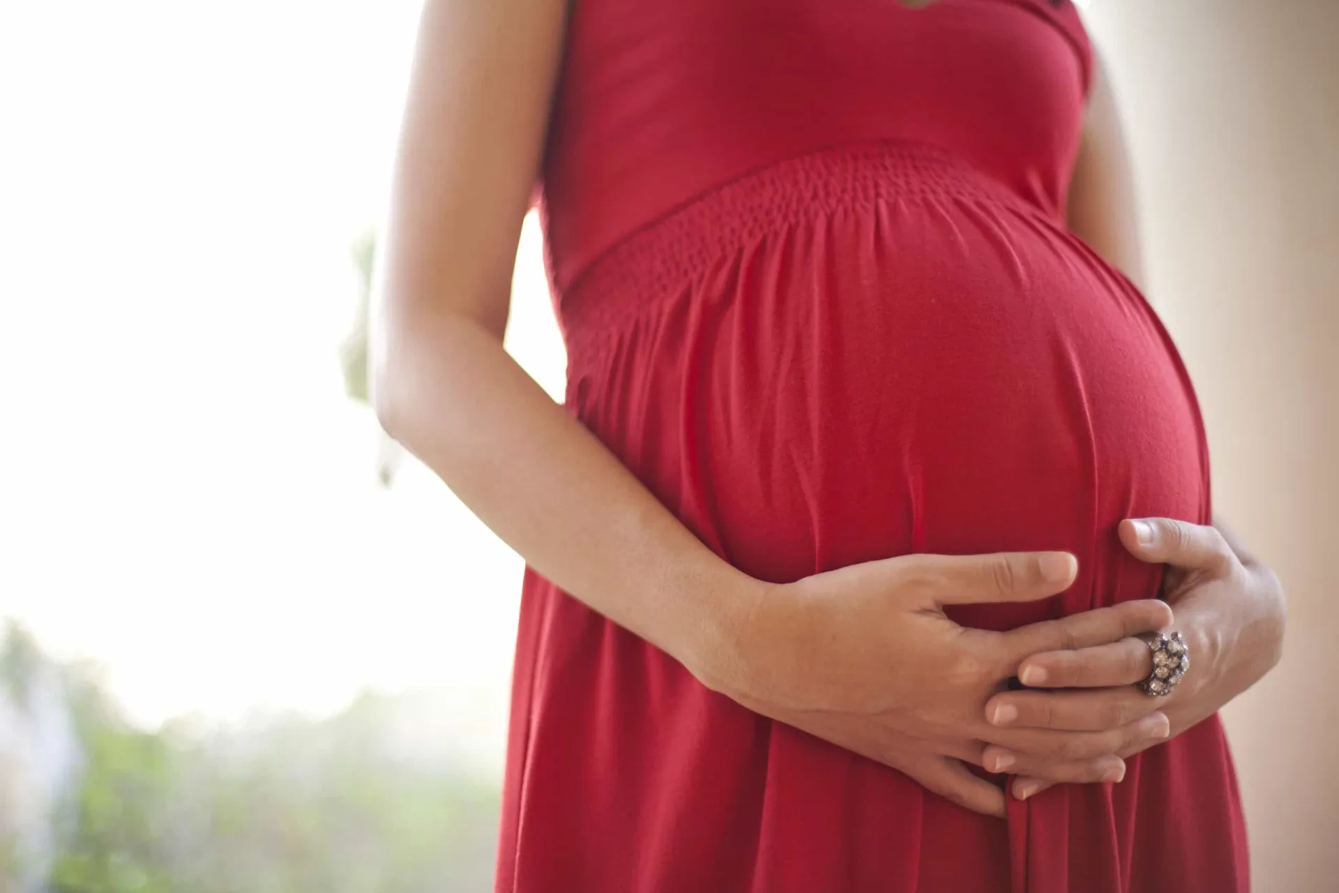 Uma mulher grávida segurando a barriga, representando o período da gestação.