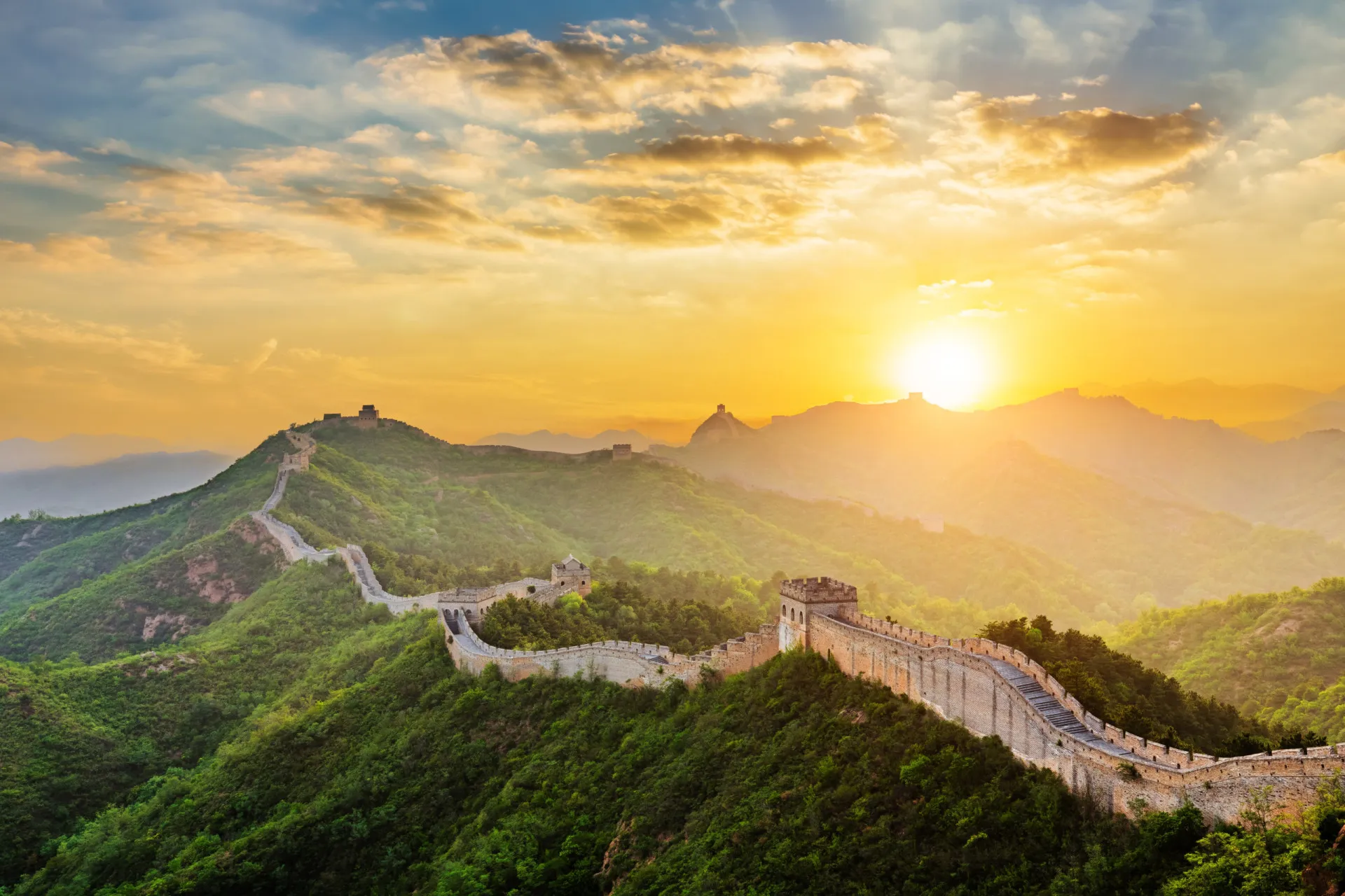 A Grande Muralha da China serpenteando pelas montanhas verdes.