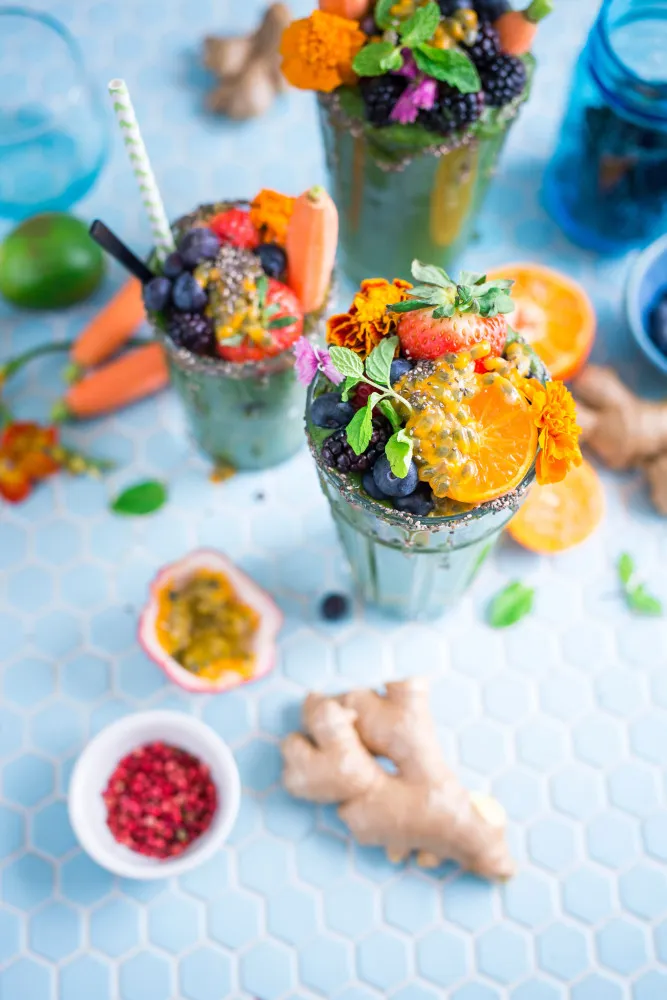 Copo de vitamina roxa decorado com frutas vermelhas e hortelã.