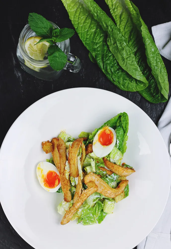 Salada com folhas verdes, pedaços de frango grelhado e ovos cozidos fatiados.