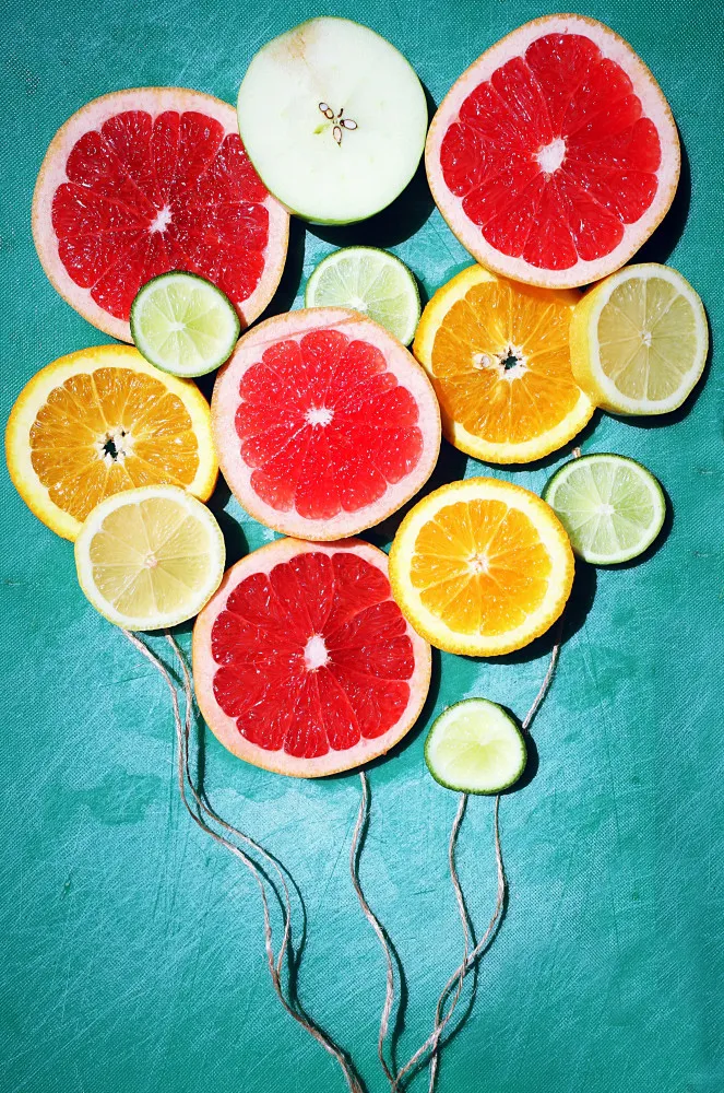 Fatias de diferentes frutas cítricas como laranja, limão e toranja, arranjadas em um prato.