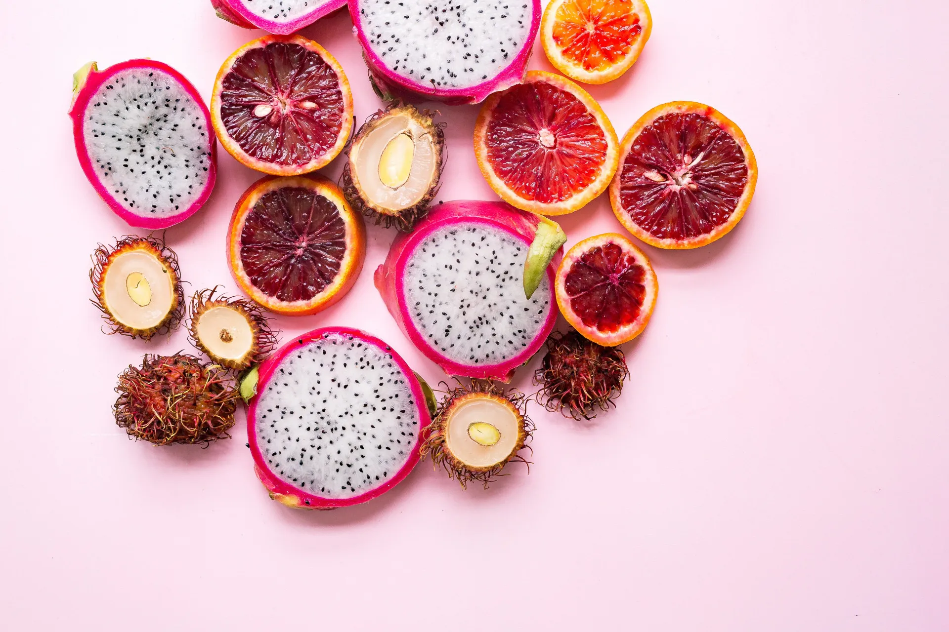 Metade de uma pitaia rosa e uma toranja cortada, exibindo suas cores vibrantes.