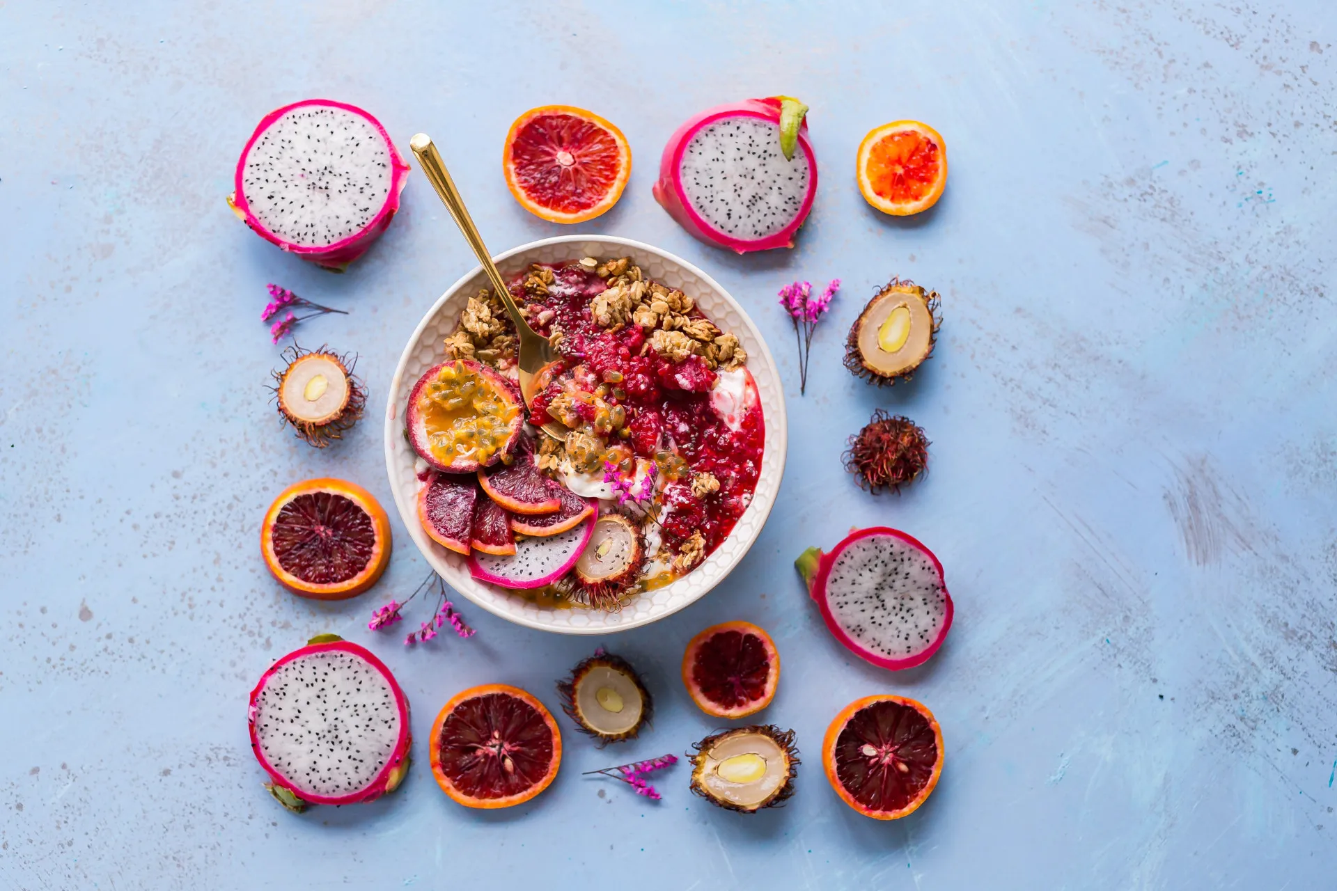 Tigela com iogurte, granola caseira e uma variedade de frutas frescas por cima.
