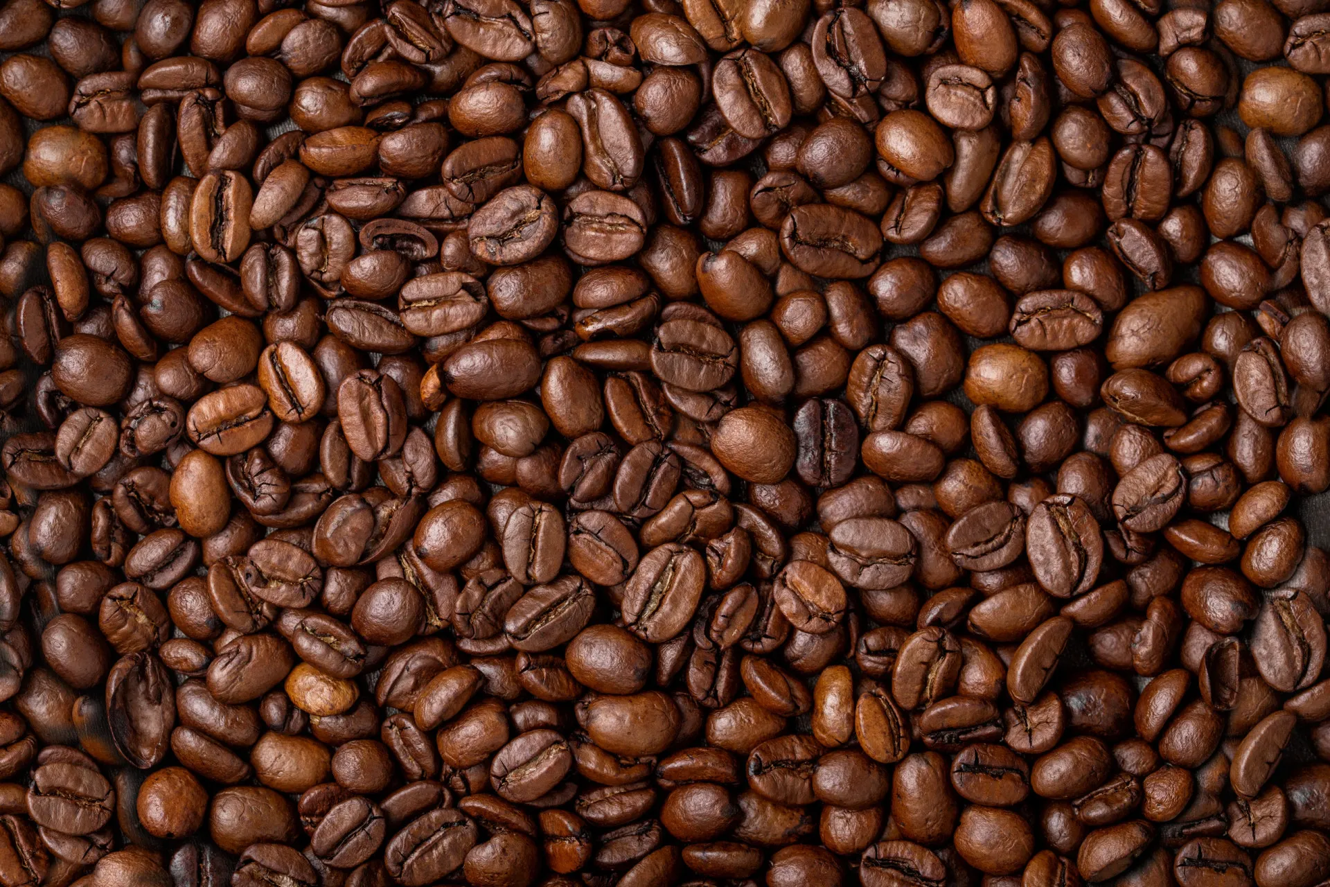 Uma pessoa com aparência cansada e com dor de cabeça, sentada em frente a uma xícara de café.