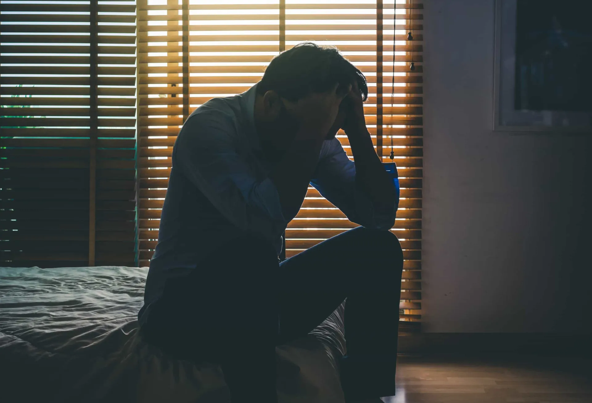 Pessoa em estado de depressão profunda, sentada em um quarto escuro e isolada.