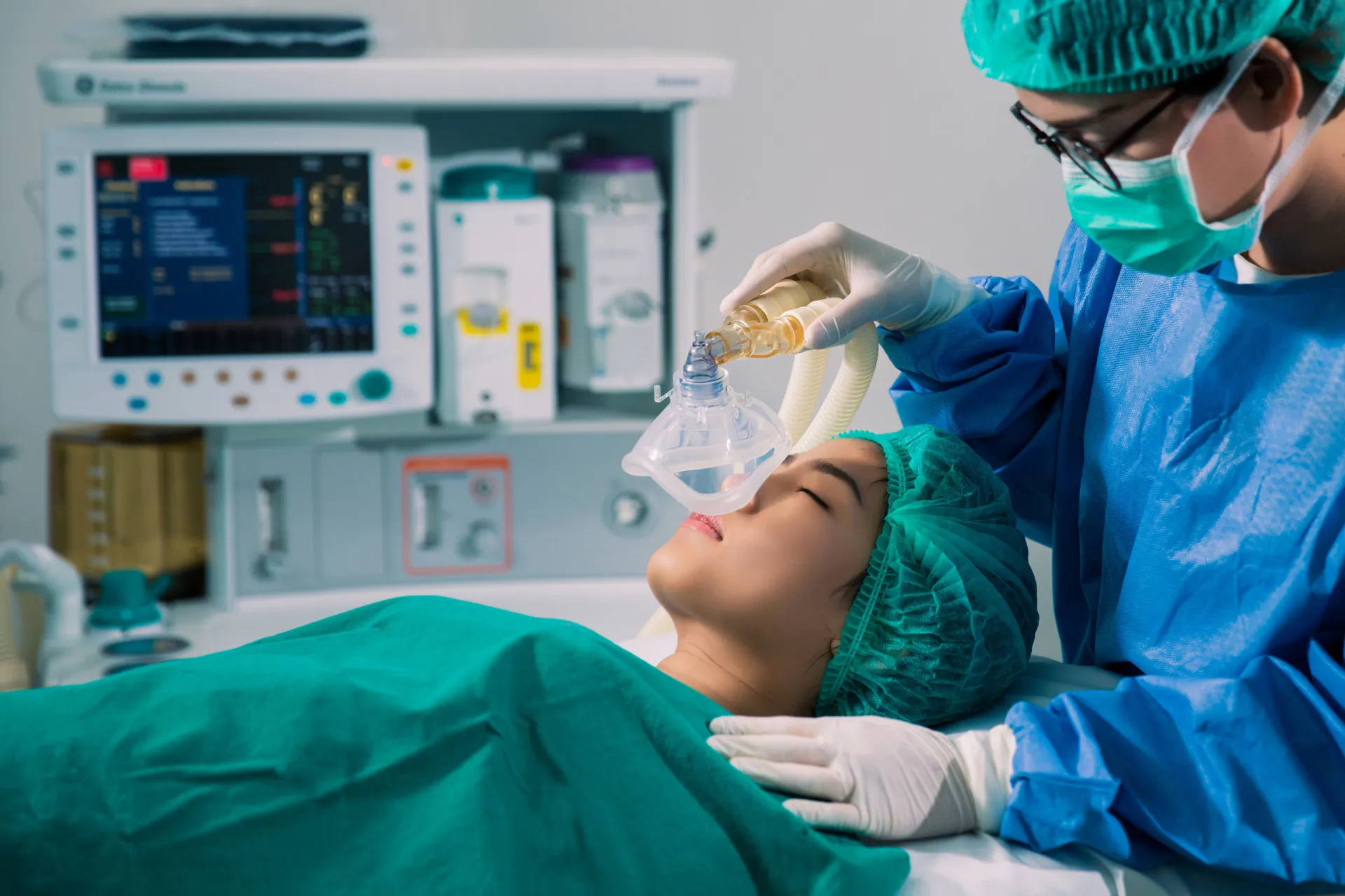 Anestesista monitorando equipamentos em uma sala de cirurgia, com foco e concentração.