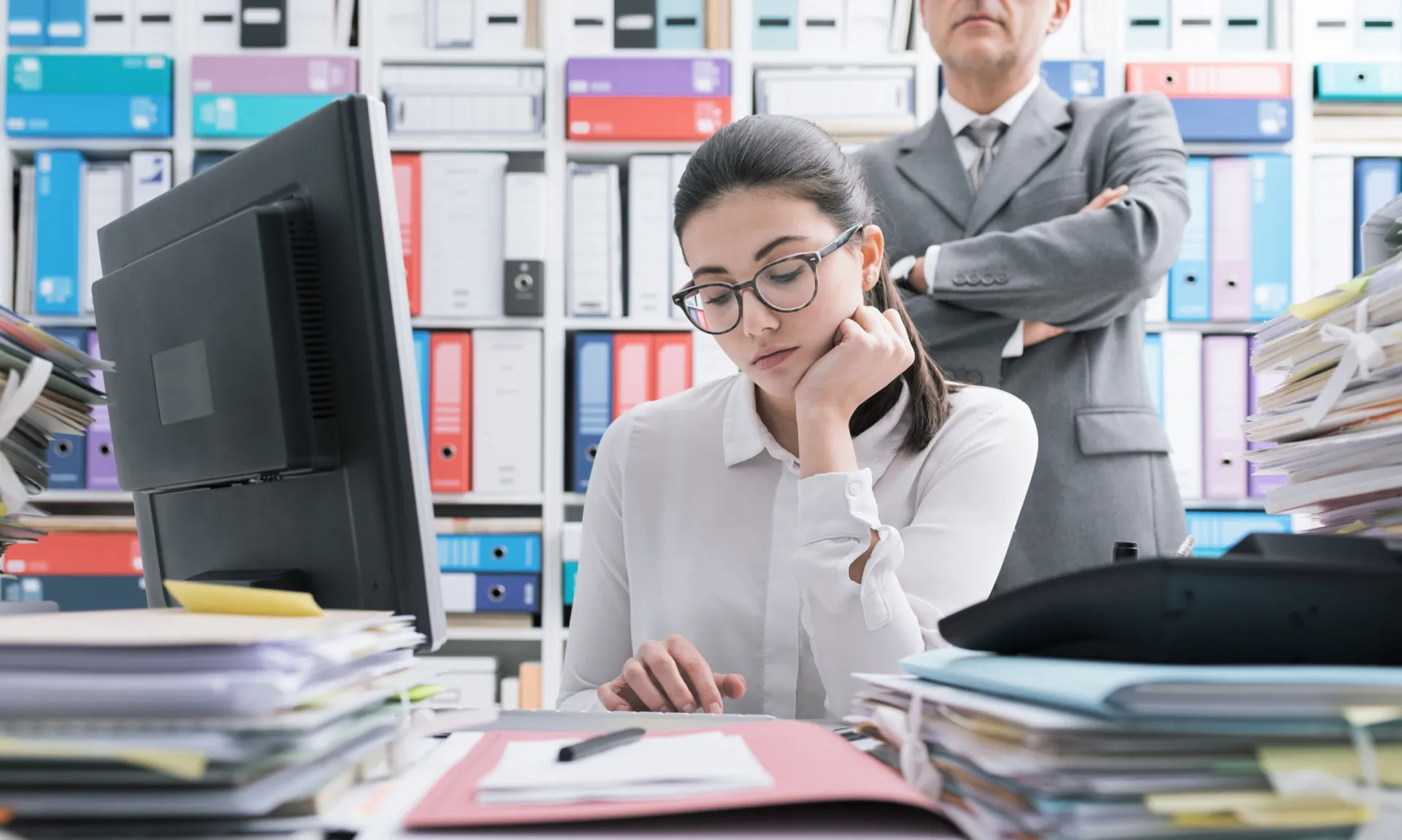 Chefe observando um funcionário por cima do ombro, ilustrando o microgerenciamento.