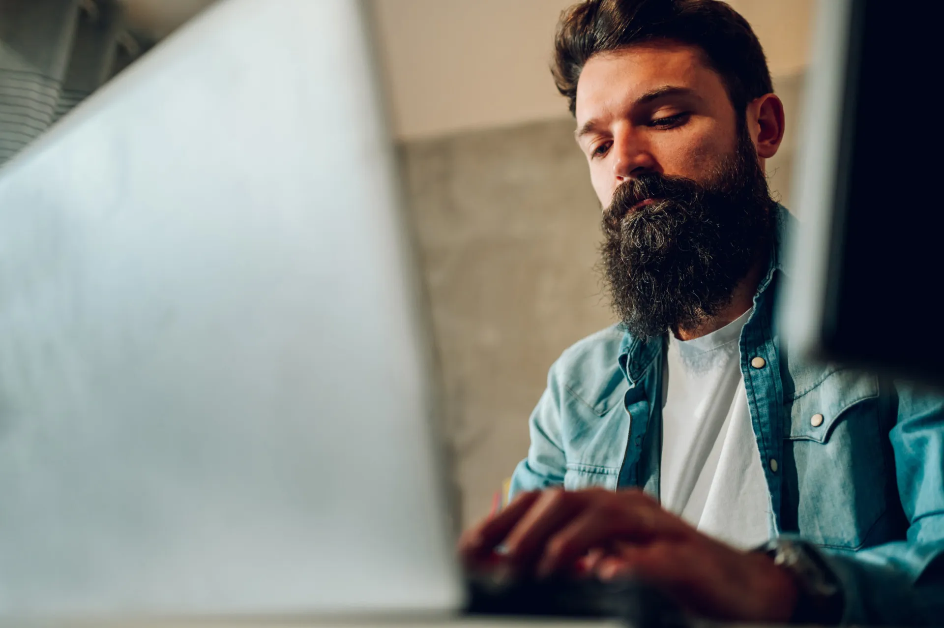 Pessoa digitando em um teclado com fones de ouvido, em um ambiente de trabalho calmo.