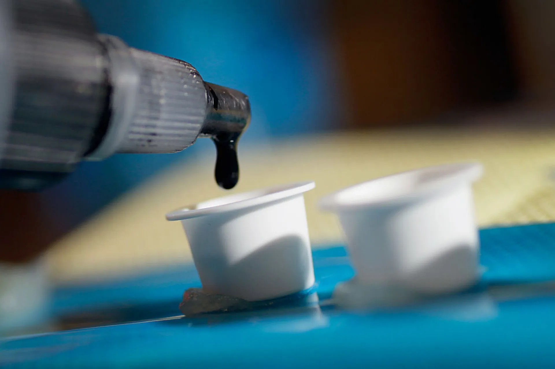 Tatuador inspecionando cuidadosamente um frasco de tinta antes de usar.